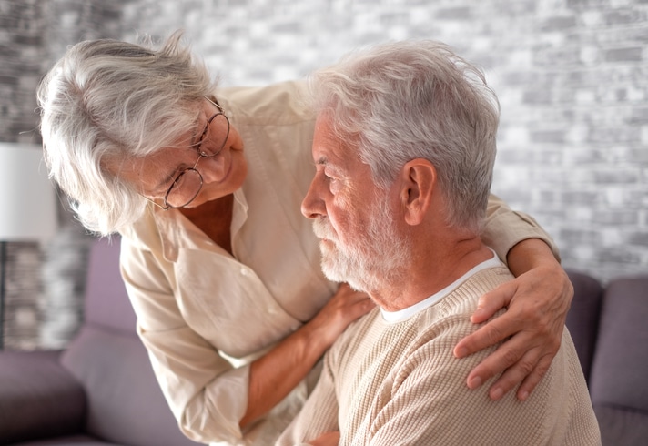 An older man who is struggling with shadowing in dementia is comforted by his wife.