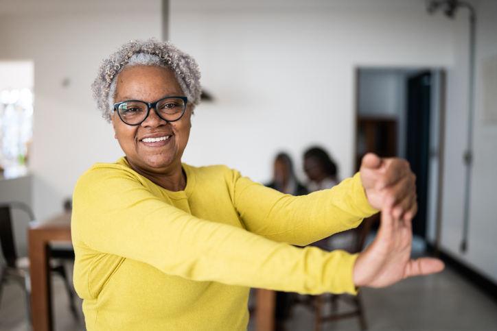 An older woman engages in stretching exercises to better manage her arthritis.