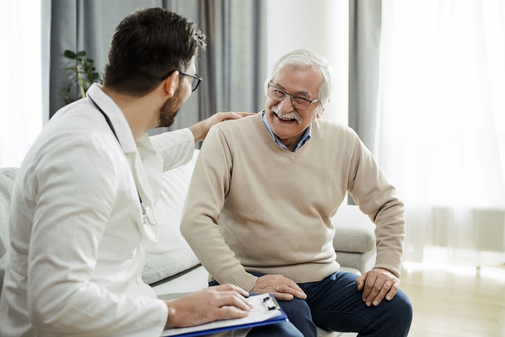 An older man smiles as he visits the doctor for a preventive healthcare checkup.