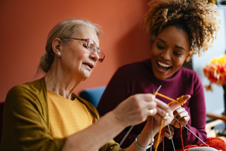A woman who is managing tremors in Parkinson’s shows her caregiver how to knit.