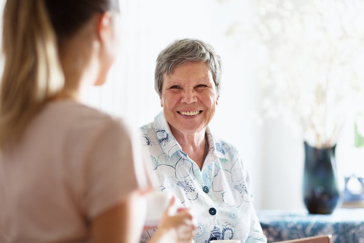 An older woman shares a warm conversation with a caregiver, supporting senior emotional heart health.